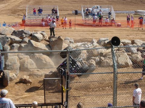 1986 Ford Bronco - An off-road buggy attempts to navigate a rocky obstacle course, while spectators watch from the stands.