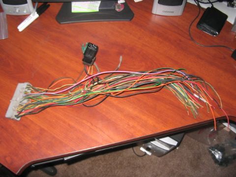 1991 Ford Bronco - A tangled wiring harness with a gray connector and a black relay sits on a wooden desk.
