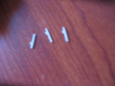 1991 Ford Bronco - Three white plastic clips are scattered on a wooden surface.
