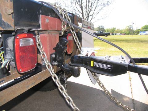 1988 Ford C-350 (Centurion Conversions) - Close-up of a trailer hitch and chains, with a pickup truck in the distance.