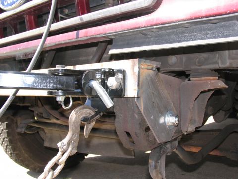 1988 Ford C-350 (Centurion Conversions) - A close-up view of a tow hitch assembly on a red truck, showing a heavy-duty chain and hook.