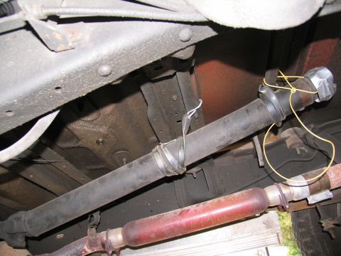1988 Ford C-350 (Centurion Conversions) - Underside view of a vehicle's driveshaft and exhaust system, secured with wire and tape.