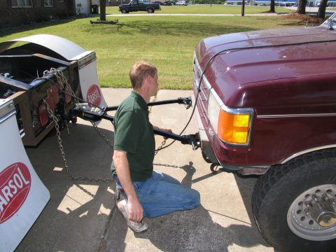 1988 Ford C-350 (Centurion Conversions) - A man kneels to connect a trailer to a maroon Ford F-Series truck, which has a 'Barsol' logo visible on the trailer.