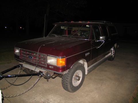 1988 Ford C-350 (Centurion Conversions) - This maroon SUV has a trailer hitch and is parked on a concrete surface at night.