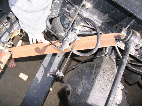 1988 Ford C-350 (Centurion Conversions) - Underneath view of a truck's chassis, showing various mechanical components and a person's hand.