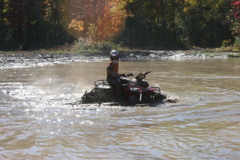 1987 Ford Bronco - Riding an ATV through a muddy water obstacle during an off-road excursion.