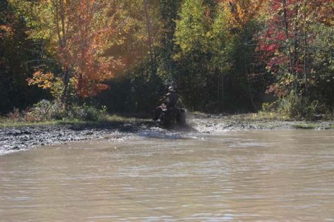 1987 Ford Bronco - An ATV navigates a muddy water crossing during autumn.