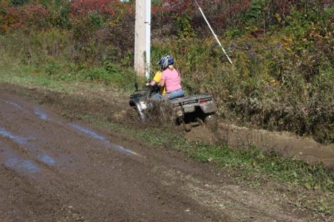 1987 Ford Bronco - An ATV is stuck in the mud on a trail, with two riders on board.