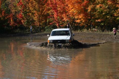1987 Ford Bronco - 1987 Ford Bronco navigates a muddy obstacle during an off-road excursion in autumn.
