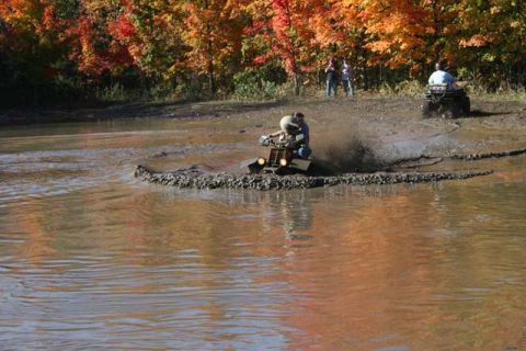 1987 Ford Bronco - Two ATVs navigate a muddy track during autumn, with colorful fall leaves overhead.