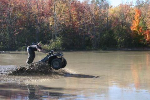 1987 Ford Bronco - ATV rider navigates through a muddy water crossing during autumn.