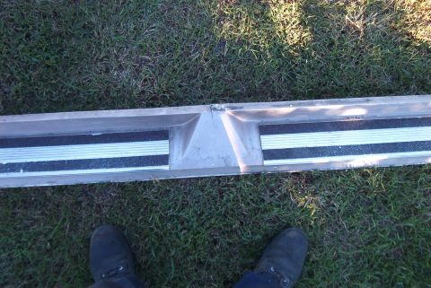 1988 Ford E250 - A running board step with textured strips is laid out on the grass. A person's feet are visible at the bottom.