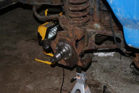 1987 Ford Bronco - Close-up view of a front wheel hub assembly, likely undergoing maintenance or repair, with a yellow work light attached.