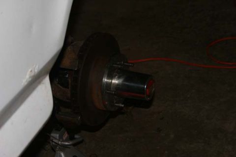 1987 Ford Bronco - The front wheel hub and brake assembly are visible, with a portion of the vehicle's white bodywork in the foreground.