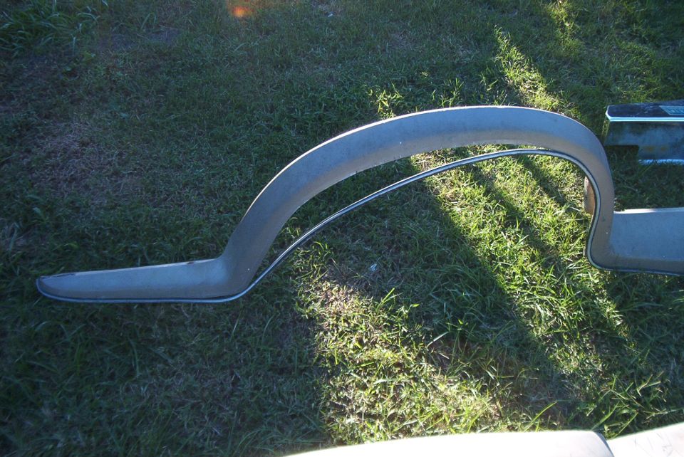 Gray fender flare with chrome trim, lying on grass