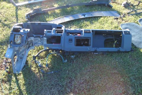 1988 Ford E250 - Dashboard assembly removed from a vehicle, lying on the grass with various wires exposed.