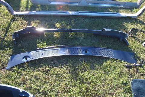 1988 Ford E250 - Various automotive parts are displayed on a grassy surface, with a focus on a black cowl vent panel.