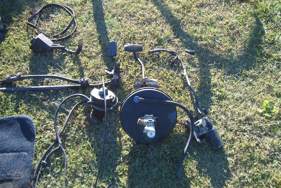 Vehicle brake booster, master cylinder, steering linkage, and other parts laid out on grass