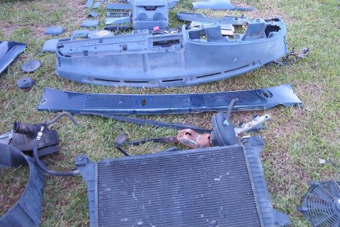 1988 Ford E250 - Various vehicle parts, including a dashboard and radiator, are spread out on a grassy surface.