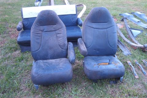 1988 Ford E250 - Two front van seats and other vehicle parts are displayed on a grassy area.
