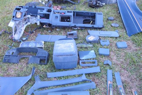 1988 Ford E250 - Various disassembled interior components of a vehicle are spread out on a grassy surface.
