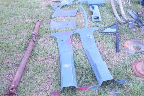 1988 Ford E250 - Collection of vehicle parts, including a driveshaft and interior trim, displayed on a grassy surface.