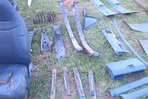 1988 Ford E250 - Assorted vehicle parts, including a seat and suspension components, are displayed on a grassy surface.