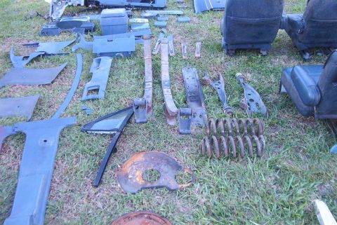 1988 Ford E250 - Collection of assorted vehicle parts, including interior trim, seats, and suspension components, displayed on a grassy area.