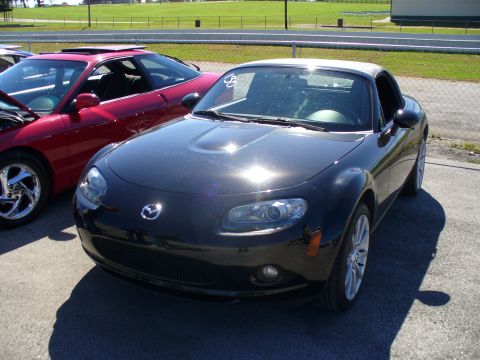 1991 Ford Probe - A black Mazda MX-5 Miata is parked in front of a red car at what appears to be a track day event.