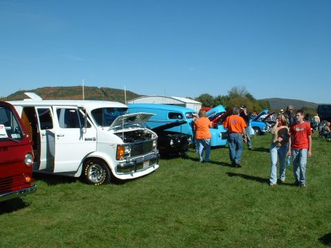 1978 Ford Mustang II - A white van is displayed with its hood open at an outdoor car show.