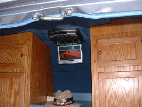 1978 Ford Mustang II - Interior view of a van, wood paneling and a flip-down screen that shows an orange vehicle.