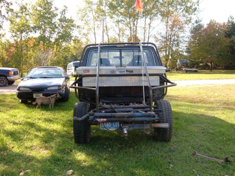 1985 Ford F-150 - A heavily modified pickup truck is parked in a grassy yard with other vehicles present.