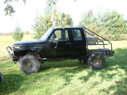 1985 Ford F-150 - Modified black pickup truck with extended cab and custom rear cage.