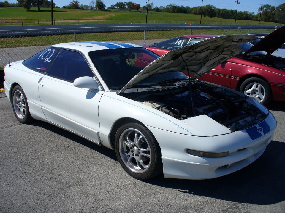 White 1991 Ford Probe with blue stripes, hood open, parked on asphalt