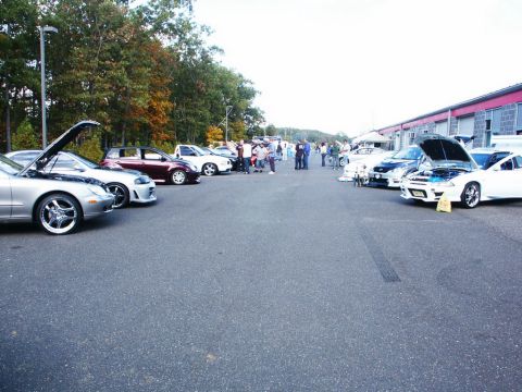 2001 Mercury Grand Marquis - A gathering of cars and people in an outdoor lot, with several vehicles displaying their engines.