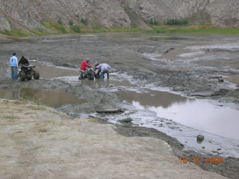 1985 Ford Bronco - ATVs are being ridden and worked on in a muddy, watery landscape.