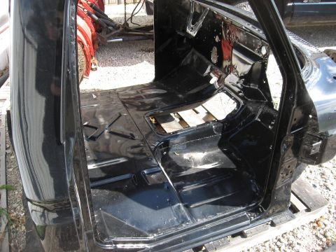 1977 Ford F-150 - Disassembled truck cab interior with black painted floor pan and exposed metalwork, likely undergoing restoration.
