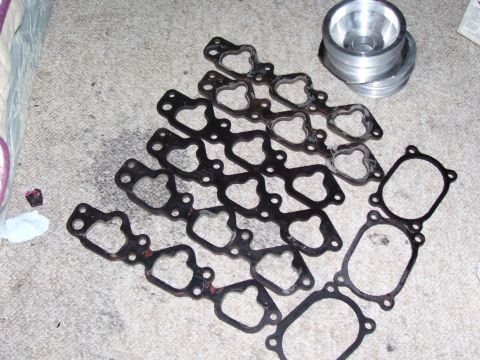 1993 Mazda MX-6 - Multiple engine gaskets and a metal adapter are laid out on a carpeted floor.