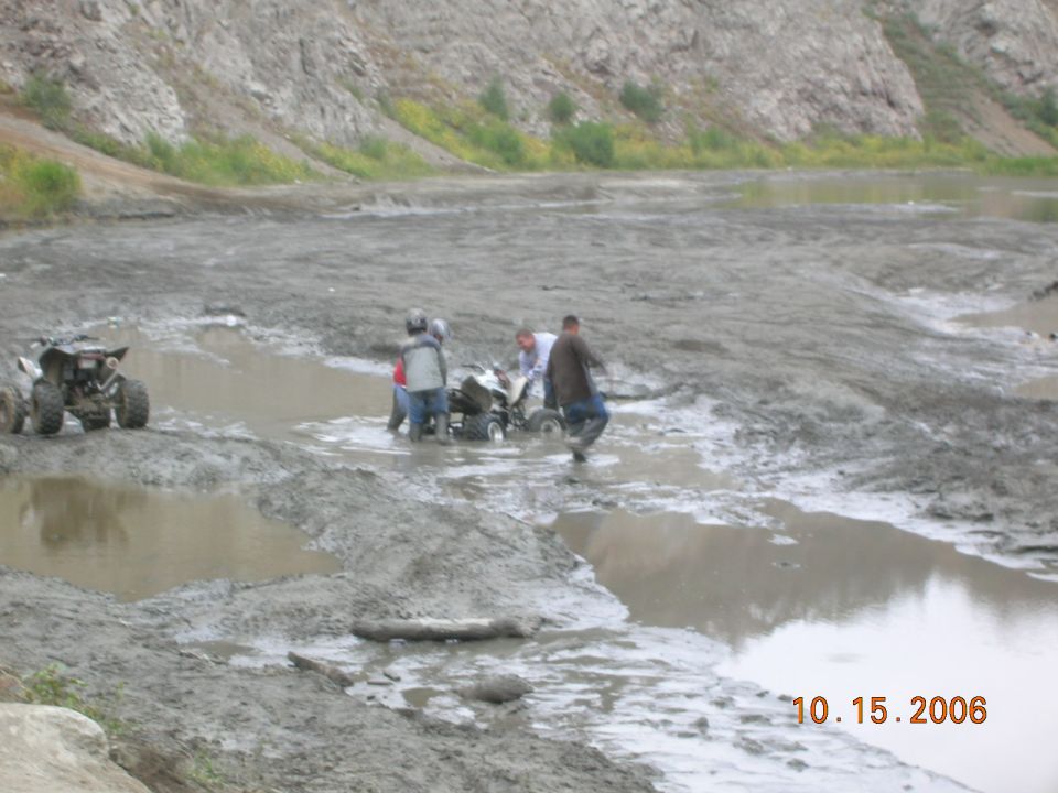 Four wheelers in muddy terrain with people riding