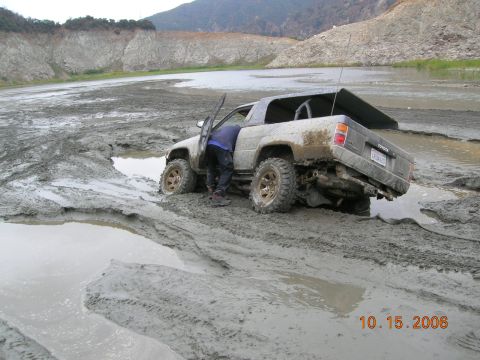 1985 Ford Bronco - A person attempts to free a Toyota 4Runner that is stuck in thick mud.