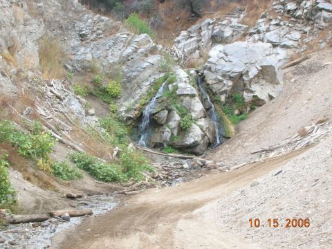 1985 Ford Bronco - A dirt path winds through a rocky canyon towards a small waterfall, with the date 10.15.2006 visible in the lower right corner.