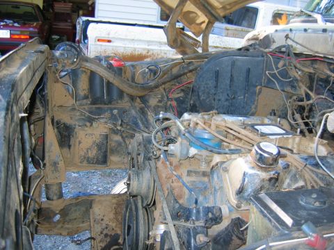 1992 Ford Mustang - The engine bay of a vehicle is shown, heavily covered in dirt and grime, with various mechanical parts visible.