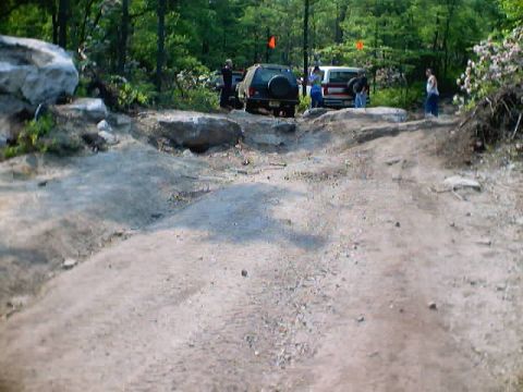 2001 Ford Escape - Two SUVs navigate a challenging off-road trail in a wooded area.