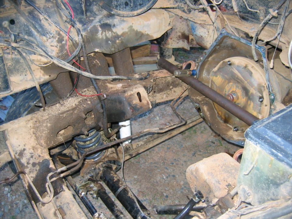Mud-covered engine bay with exposed suspension and wiring