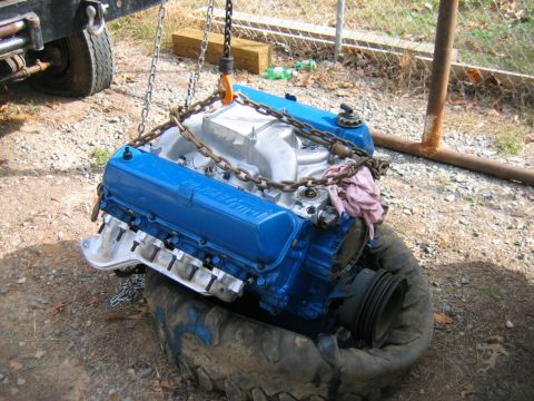 1992 Ford Mustang - A blue Ford V8 engine, likely a 460 swap, is hoisted by chains, resting on a tire.