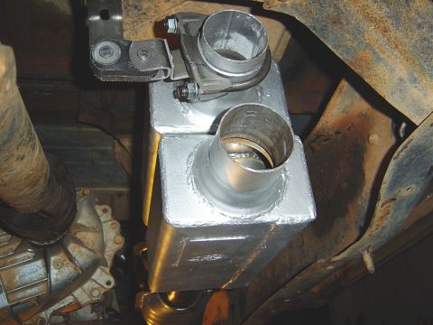 1986 Ford Bronco - Underbody view of a freshly welded aluminum or stainless steel muffler/resonator box with two exposed pipe stubs, one fitted with a band cl…