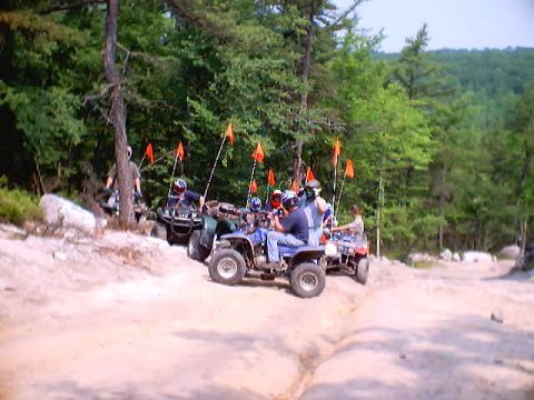 2001 Ford Escape - ATVs with riders and safety flags on a dirt trail in a wooded area.