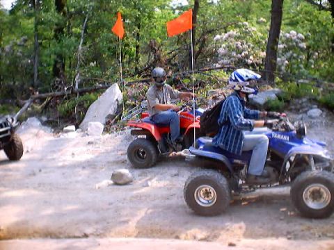 2001 Ford Escape - Two ATVs ride on a dirt path through a wooded area, marked by orange flags.