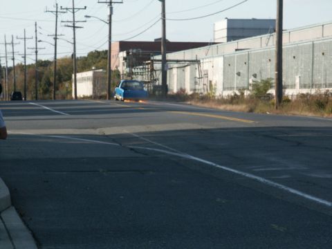 2001 Mercury Grand Marquis - A blue car appears to be on fire as it drives down an industrial road.
