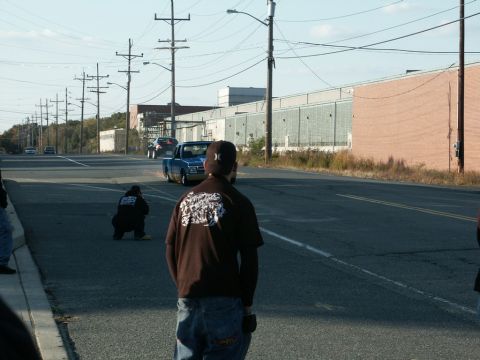 2001 Mercury Grand Marquis - A blue pickup truck performs a burnout on a street, observed by onlookers.